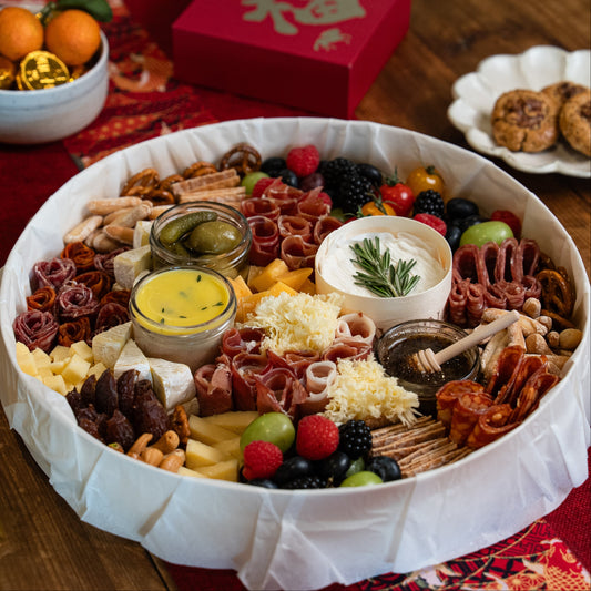 assorted charcuterie board with meats, cheeses, and fruits on a wooden table.